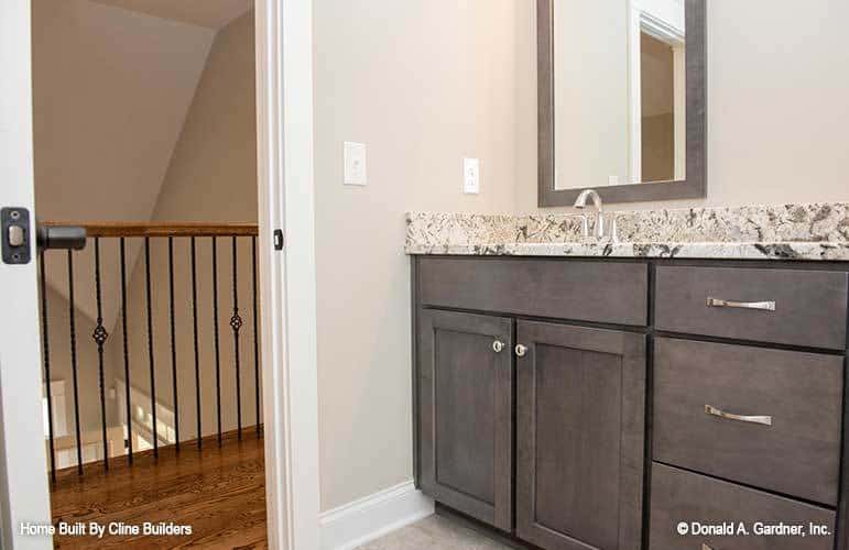 A bathroom near the balcony loft with a granite top vanity and a wooden framed mirror.