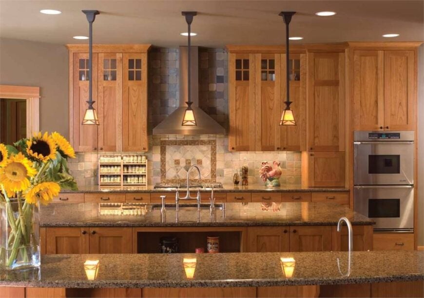 Kitchen with granite countertops, stainless steel appliances, wooden cabinetry, and small glass pendants.