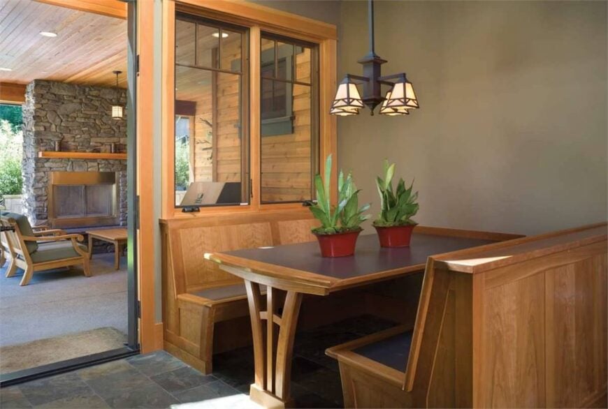 Breakfast nook with built-in table and seats well-lit by a wrought iron chandelier.