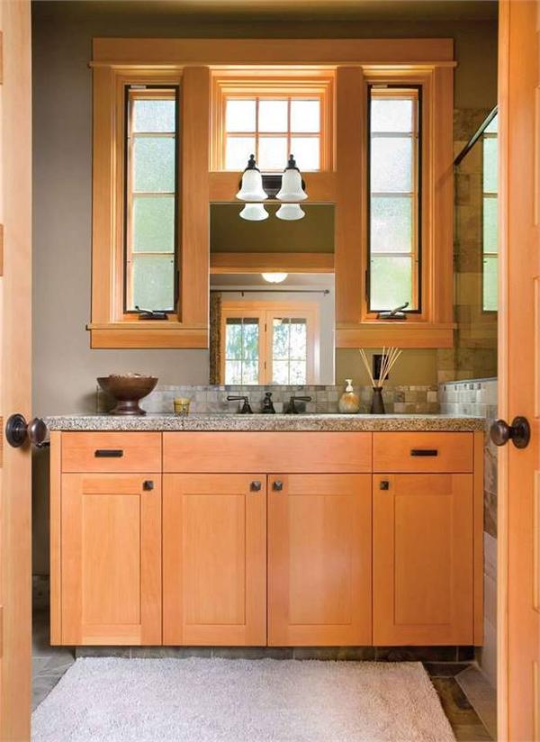 Powder room with a smooth wooden vanity topped with granite countertops and wrought iron fixtures.