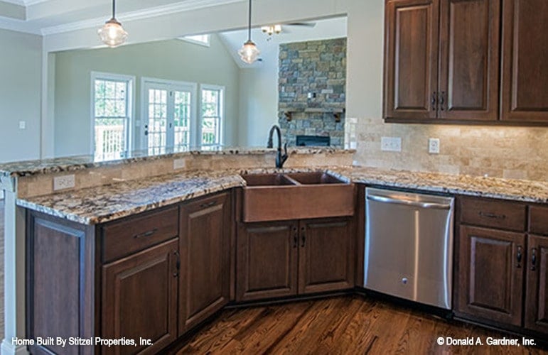 The kitchen peninsula is fitted with a farmhouse sink, dishwasher, and two-tier granite countertops.