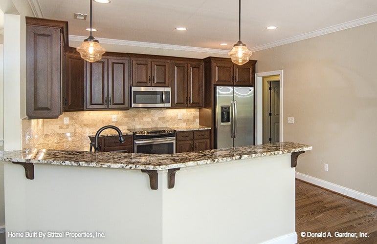 A pair of glass pendants along with recessed ceiling lights illuminate the kitchen.