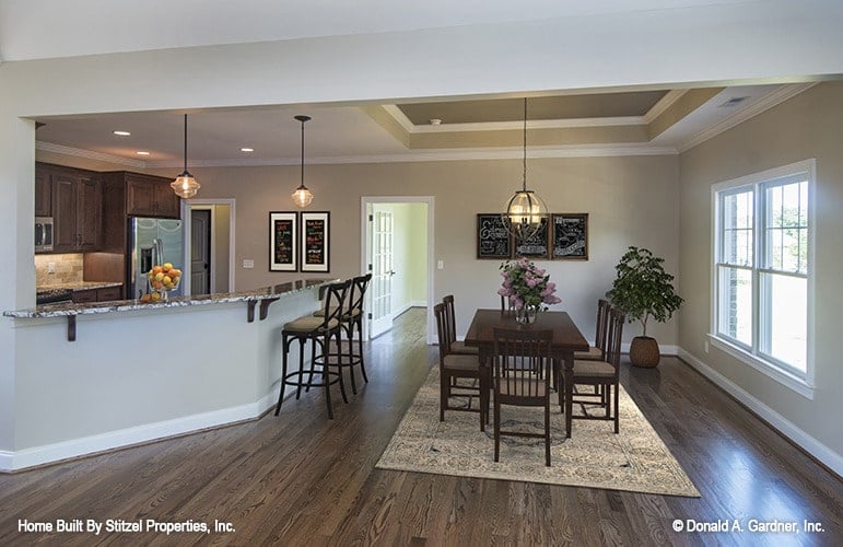 The dining area has a spherical chandelier, rectangular dining table, and cushioned chairs sitting on a patterned area rug.