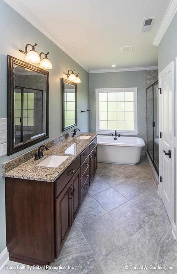 The primary bathroom is equipped with his and her vanity, freestanding tub, toilet room, and a walk-in shower.