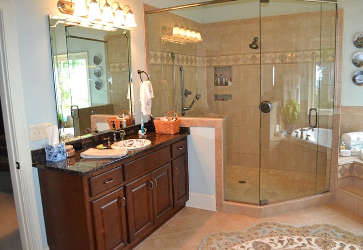 The primary bathroom has a dark wood vanity and a walk-in shower fitted with inset shelves and chrome fixtures.