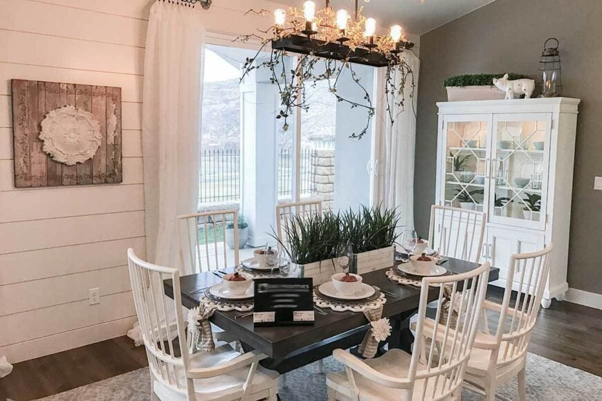 The dining area offers a display cabinet, white armchairs, a dark wood coffee table, and a linear chandelier.
