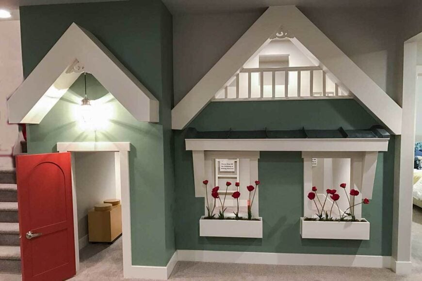 Kids' playroom showcasing a red front door, green walls, planter boxes, and gable rooflines.