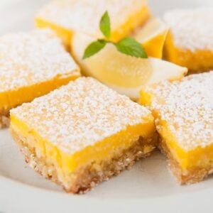 A close look at a plate of lemon bars with powdered sugar toppings.