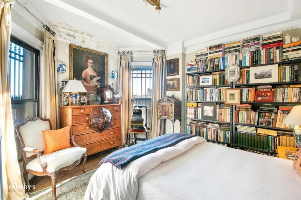 This is the bedroom with a built-in bookshelf on the side and a wooden dresser across from the bed topped with a painting. Image courtesy of Toptenrealestatedeals.com.