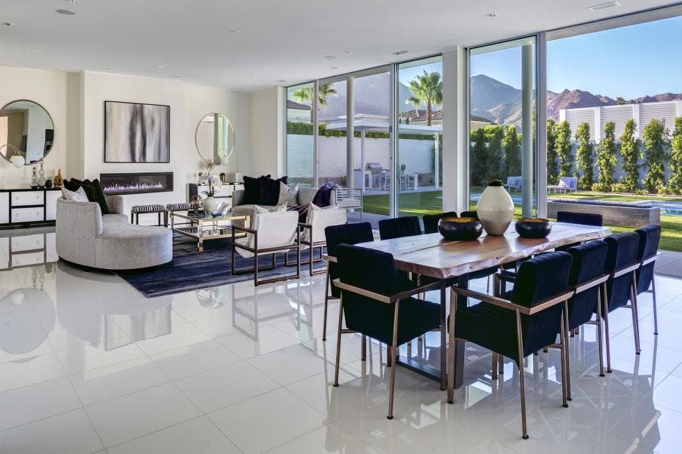 This is a look at the dining area just a few steps from the living room. This has a wooden dining table surroynded by dark chairs to contrast the white floor and the bright glass wall. Image courtesy of Toptenrealestatedeals.com.