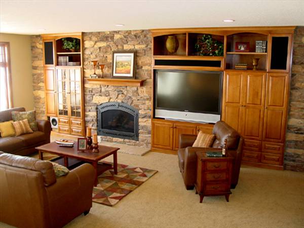 The family room has a stone fireplace, wooden built-ins, and brown leather seats paired with a wooden coffee table.