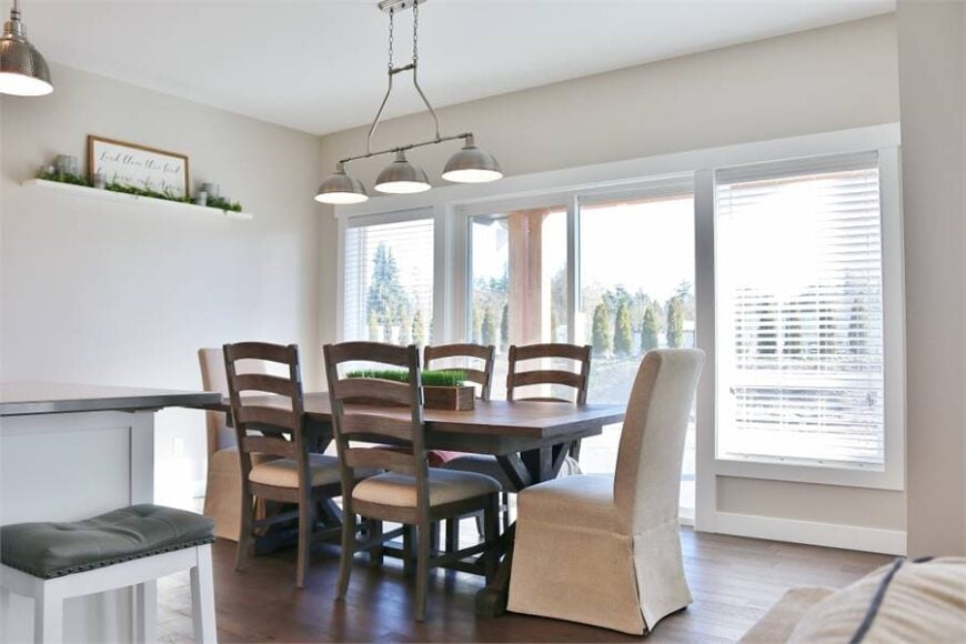 The dining room has cushioned and skirted chairs, a wooden dining table, and chrome dome pendant lights.