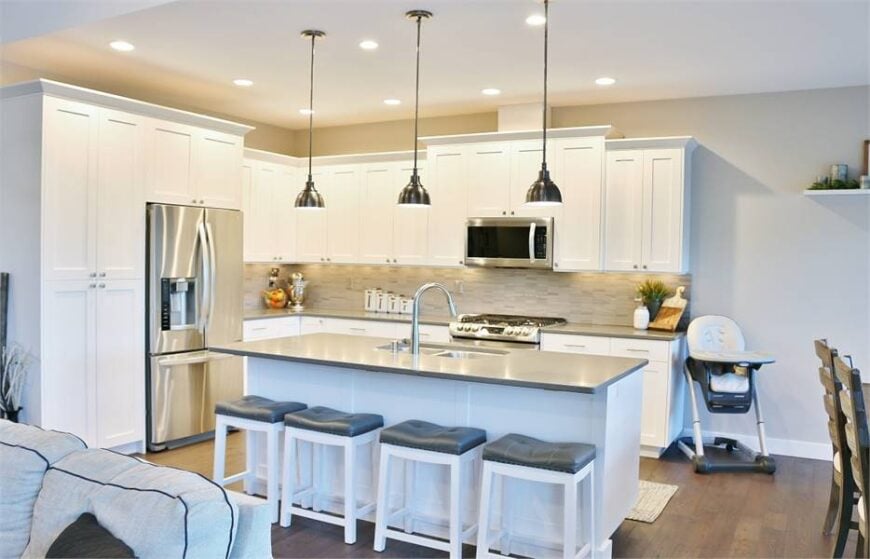 Chrome dome pendants and cushioned bar stools complement the kitchen island.