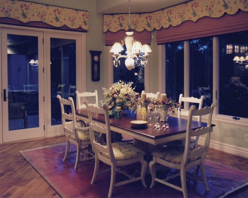 Formal dining room with cushioned chairs, wooden dining table, and a warm glass chandelier.