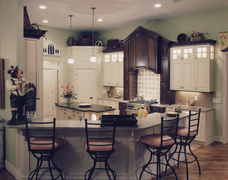 Kitchen with white cabinetry, center island, and a curved peninsula complemented with cushioned counter chairs.