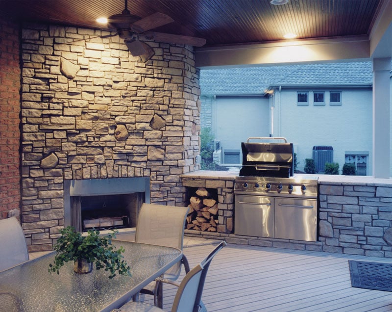 The covered porch is filled with an outdoor dining, summer kitchen, and a matching stone fireplace.