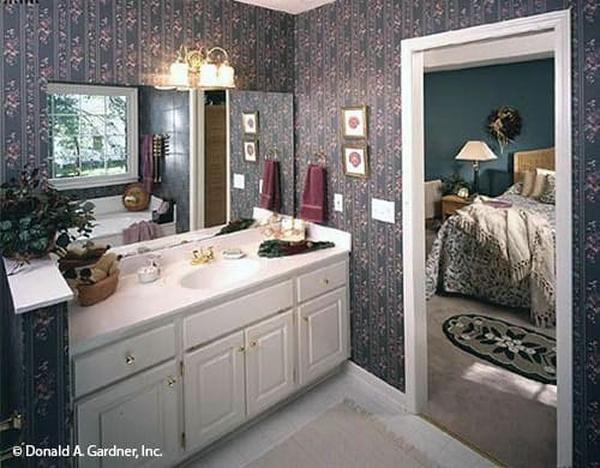 The primary bedroom has a cozy bed, wicker dressers, blue walls, and a high coved ceiling.