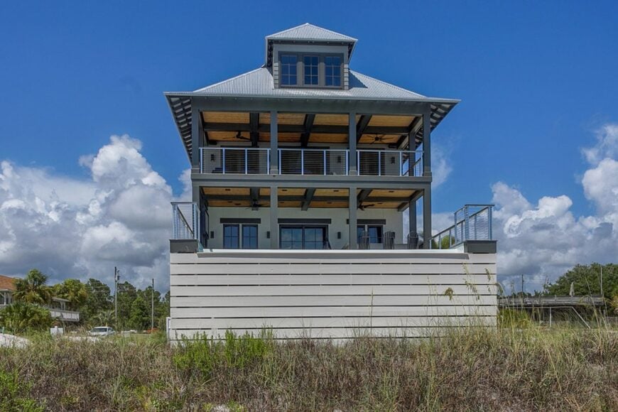 Rear exterior view showing the wide balconies, gray columns, and a large dormer gracing the hipped roof.