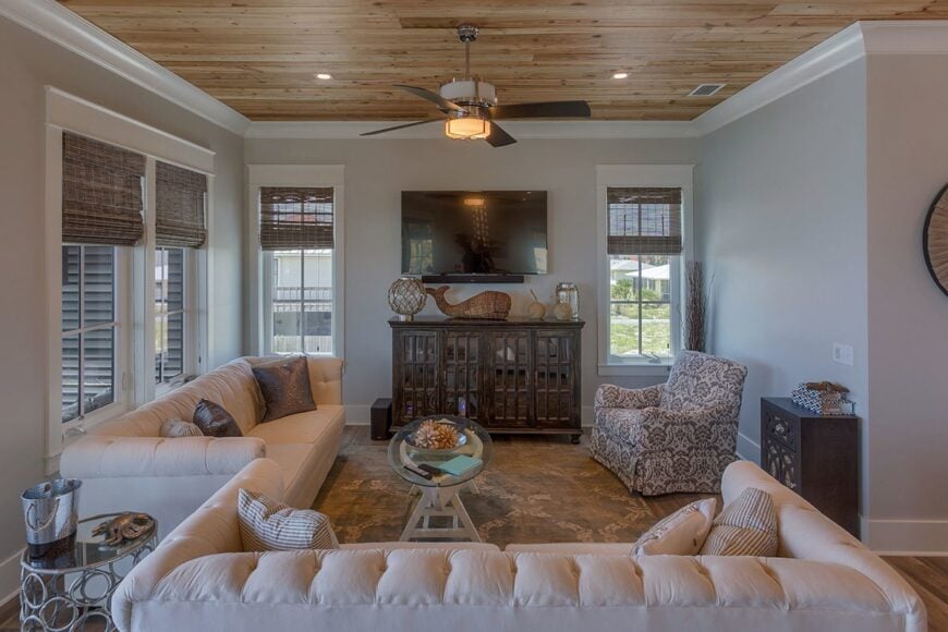 Living room with chesterfield sofas, patterned armchair, a TV, and wooden tables.