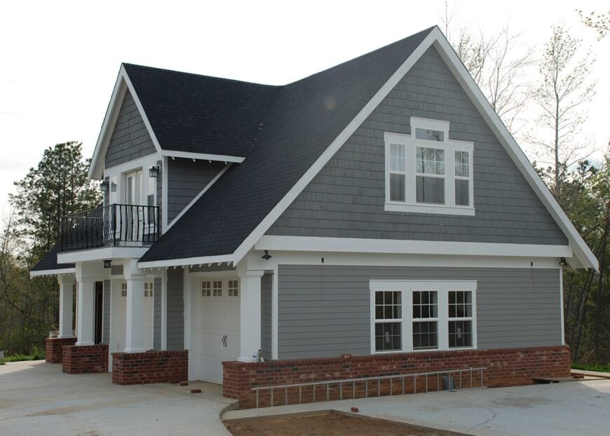 Right side view showing the gable rooflines, brick accents, cedar shingles, anf gray exterior siding.