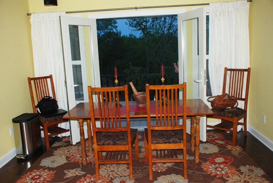 The dining area offers cushioned chairs, a rectangular table, and a french door that opens to a deck.