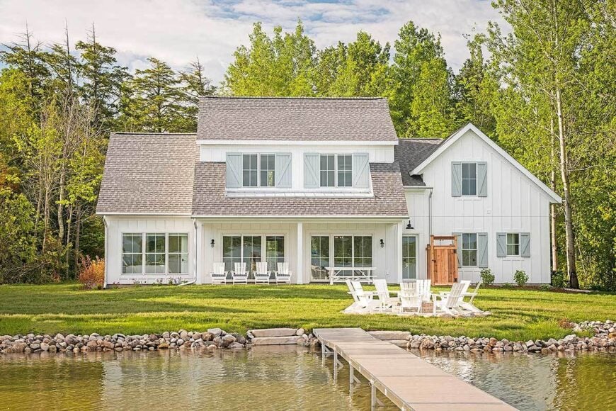 Rear exterior view with shed dormers, covered porches, fire pit seating, and a private dock.