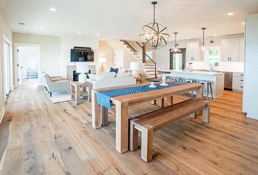The dining area has a spherical chandelier, wooden benches, and a matching dining table lined with a blue dotted runner.