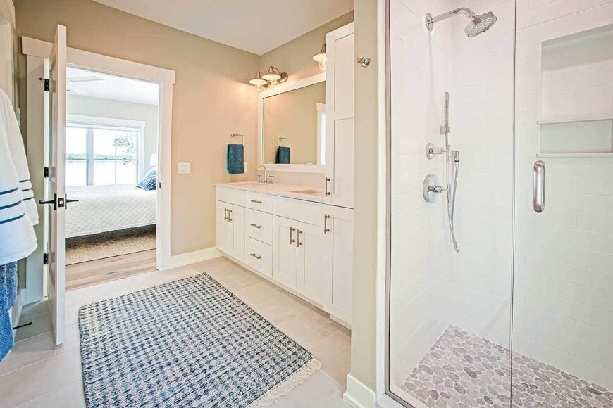 The primary bathroom has a walk-in shower and a white vanity complemented with a blue patterned rug.