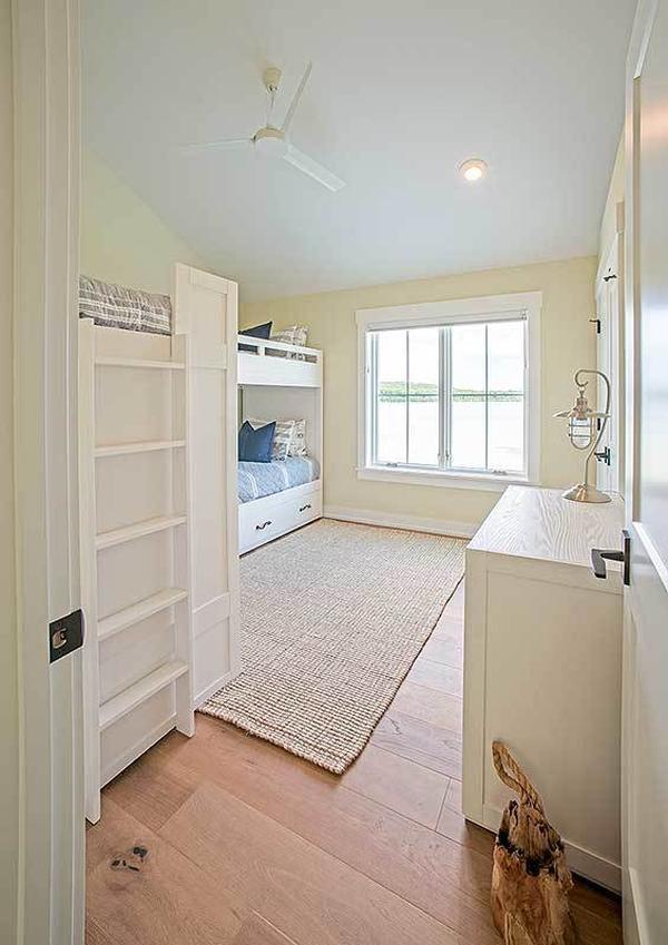 Bedroom with custom bunkbeds, light wood dresser, and white framed windows.