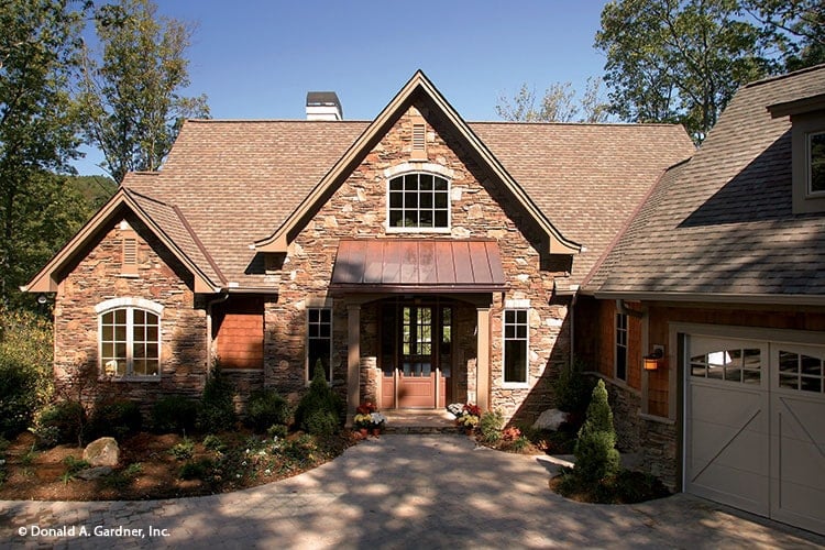 Front exterior view showing the angled garage, stone accents, and a covered entry topped with a shed roof.