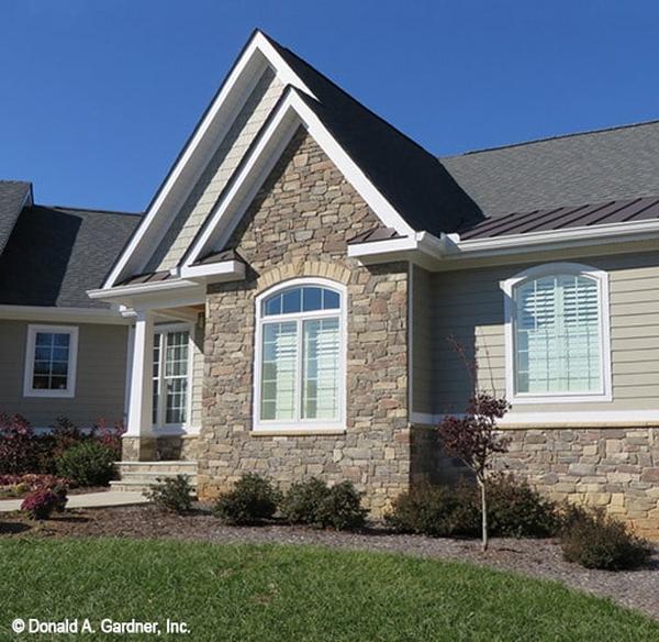 Home facade showing the stone exterior, gable rooflines, and arched windows.