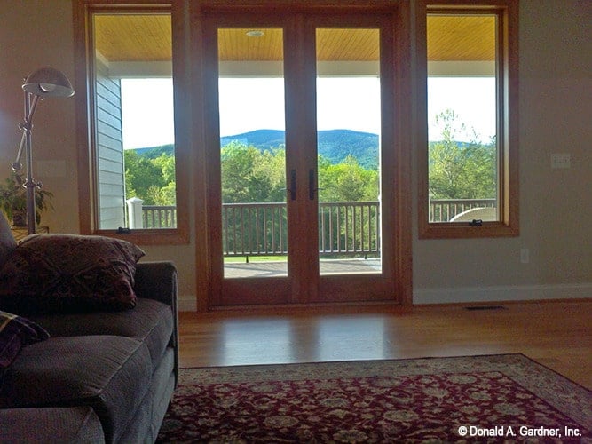 The living room has a gray sectional, red patterned area rug, and a french door that opens out to the rear deck.