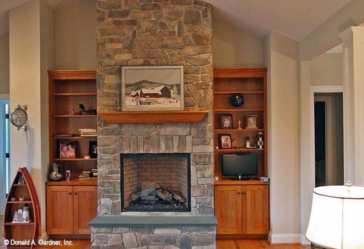 Wooden built-ins flanked the stone fireplace that's topped by a landscape artwork.