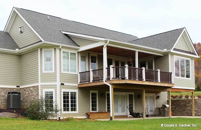 Rear exterior view with covered patio and an upper deck supported by wooden columns.