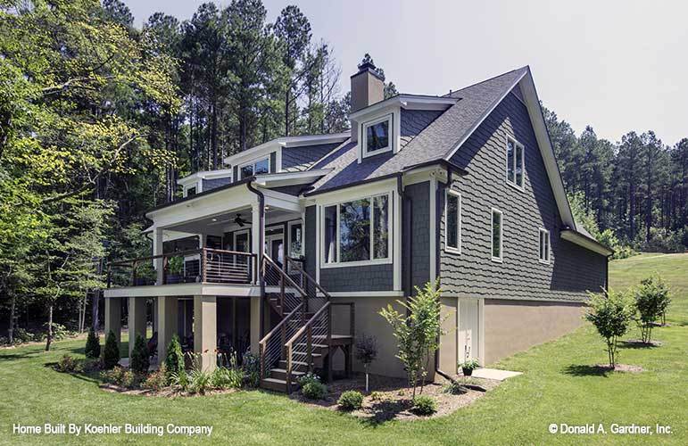 The opposite view shows the cedar shingles, metal staircase, and an expansive sloping lot.