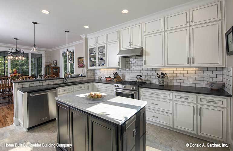 White cabinets wrap around the black island that's topped with a contrasting marble countertop.
