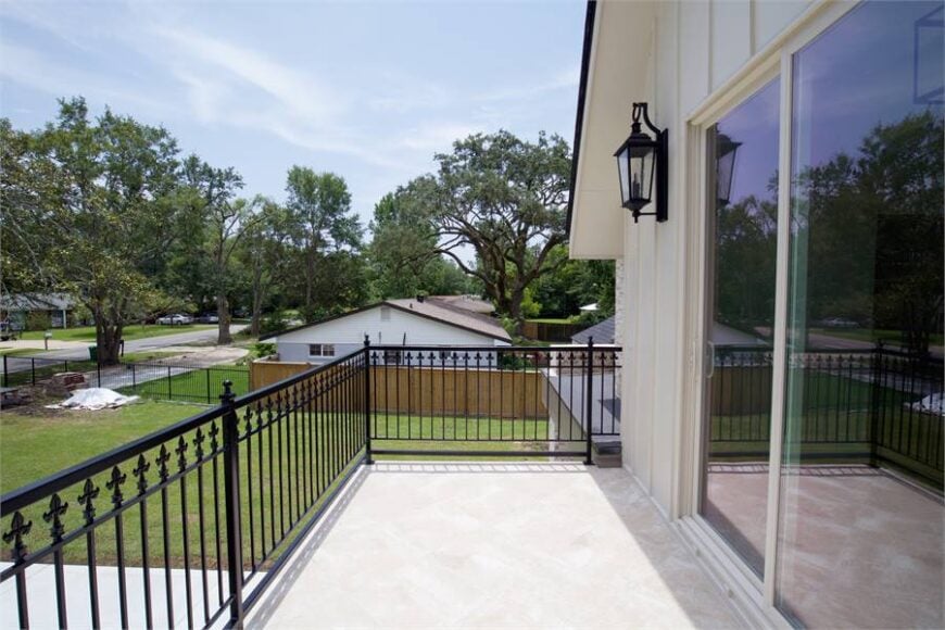 Sliding glass doors open to this balcony framed with ornate wrought iron railings.
