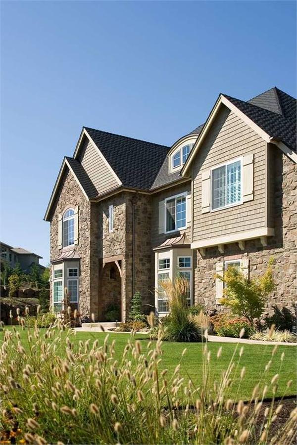 Rear exterior view with a covered porch that transitions to a lush green lawn.