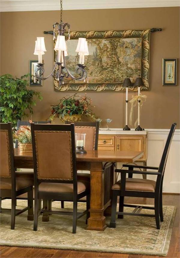 The dining room has an ornate chandelier, rectangular dining set, buffet bar, and brown walls adorned with classic framed artwork and white wainscoting.