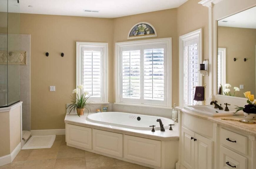 Primary bathroom equipped with a walk-in shower, sink vanity, and a corner tub placed under the bay window.