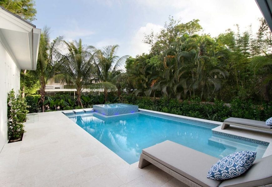 Sun deck with gray loungers and a swimming pool with an integrated spa.