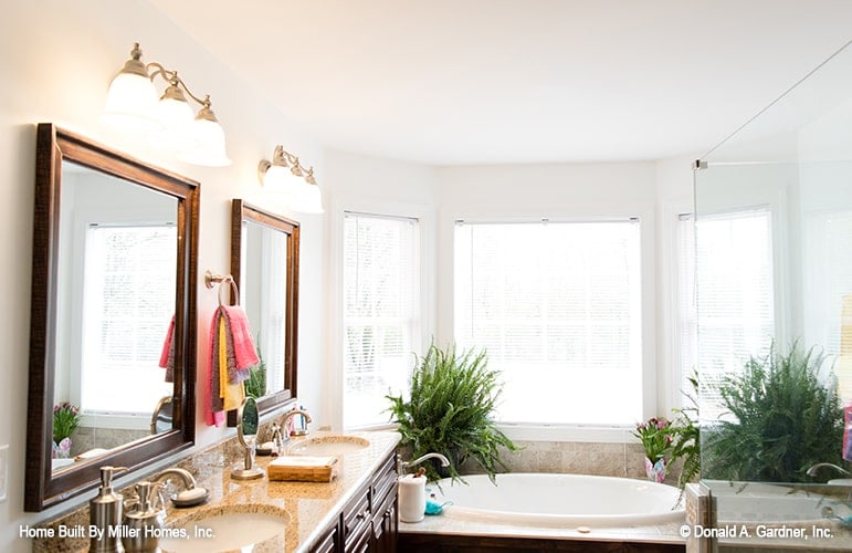 The primary bathroom has his and her vanity, a walk-in shower, and a drop-in bathtub fixed against the bay window.
