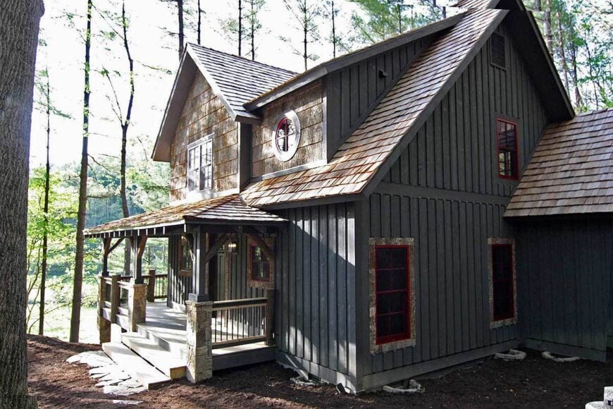 Right exterior view showing the vertical siding, red-framed windows, and a covered porch.