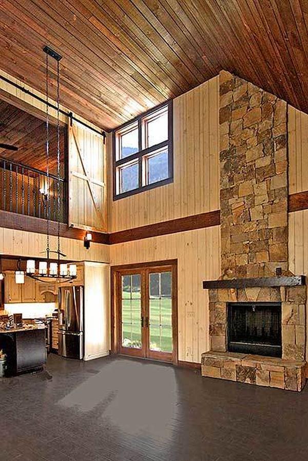 Living room with a towering wood-paneled ceiling, wide plank flooring, and a stone fireplace.