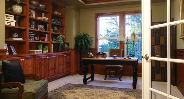 Study with cushioned chairs, a wooden desk, and a built-in bookcase.