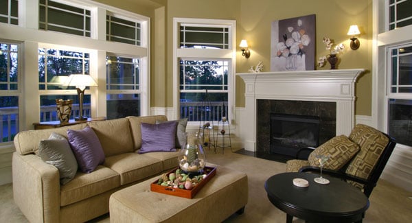 The living room has a marble fireplace, patterned armchair, beige sectional, and a matching ottoman.