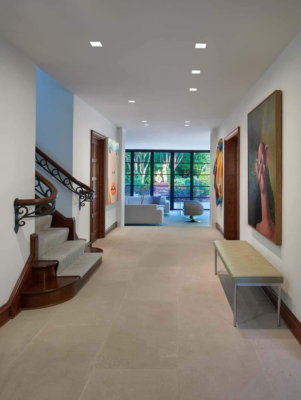 Upon entry of the house, you are welcomed by this foyer that has a cushioned bench under a large painting across from the foot of the stairs.