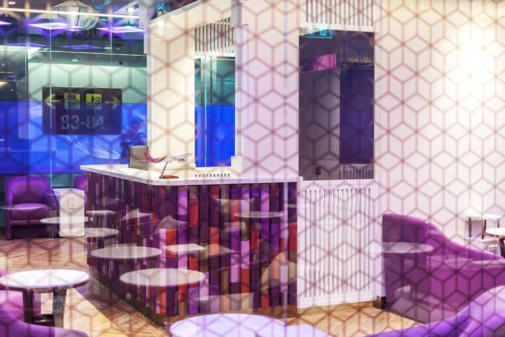 A patterned glass wall shows the canteen-like area of the lounge with orchid purple tones.