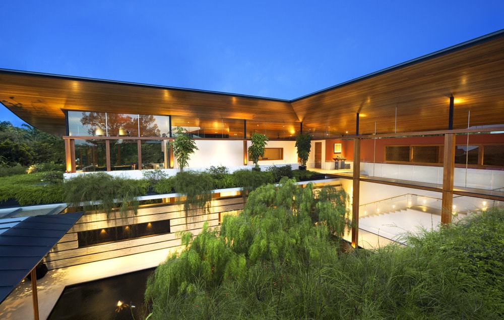 This nighttime view of the house showcases the warm glow of the interior and exterior lights that seem to mesh together complemented by the landscaping.