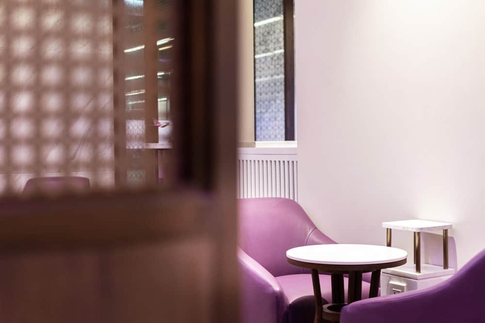 This is a close look at a a pair of purple armchairs paired with a small white coffee table in the middle.